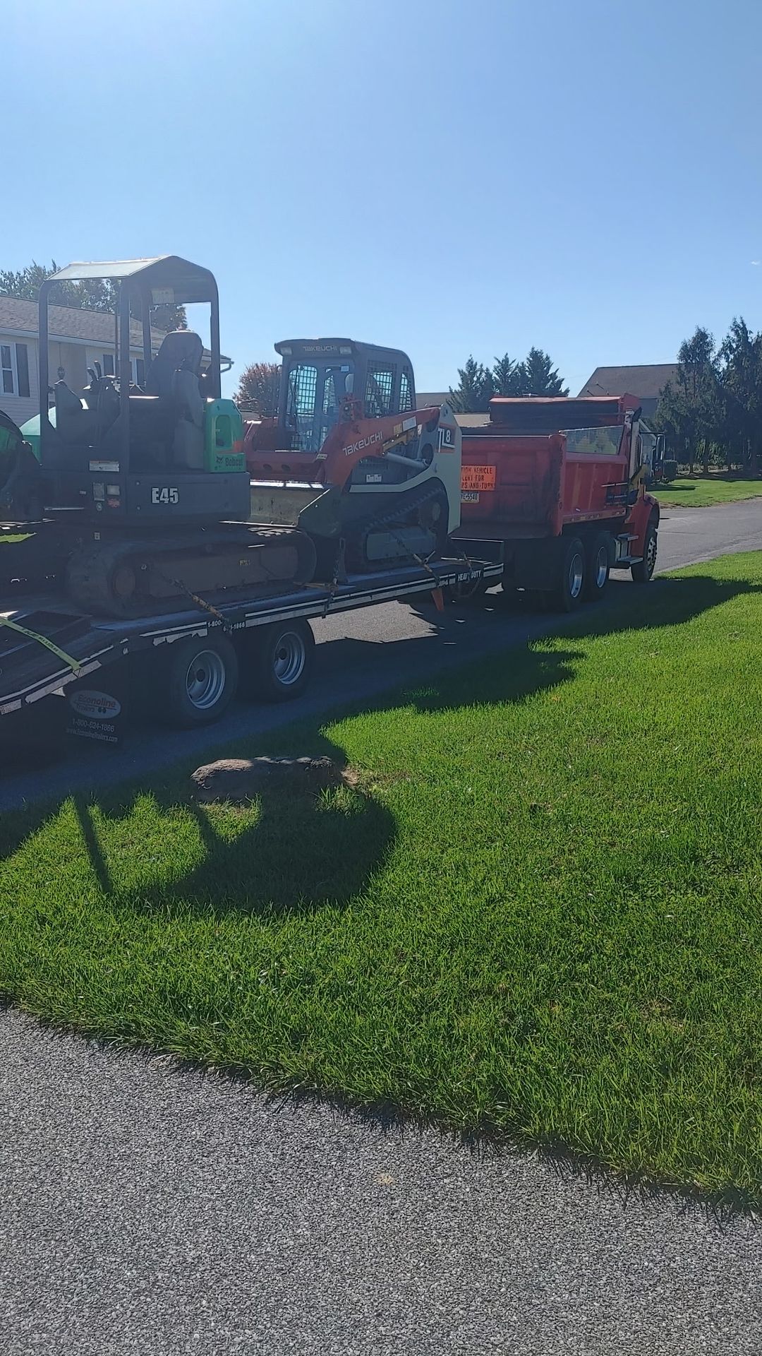Mini excavator and dump truck arriving on site for a backyard brush clearing job in Mount Joy, PA