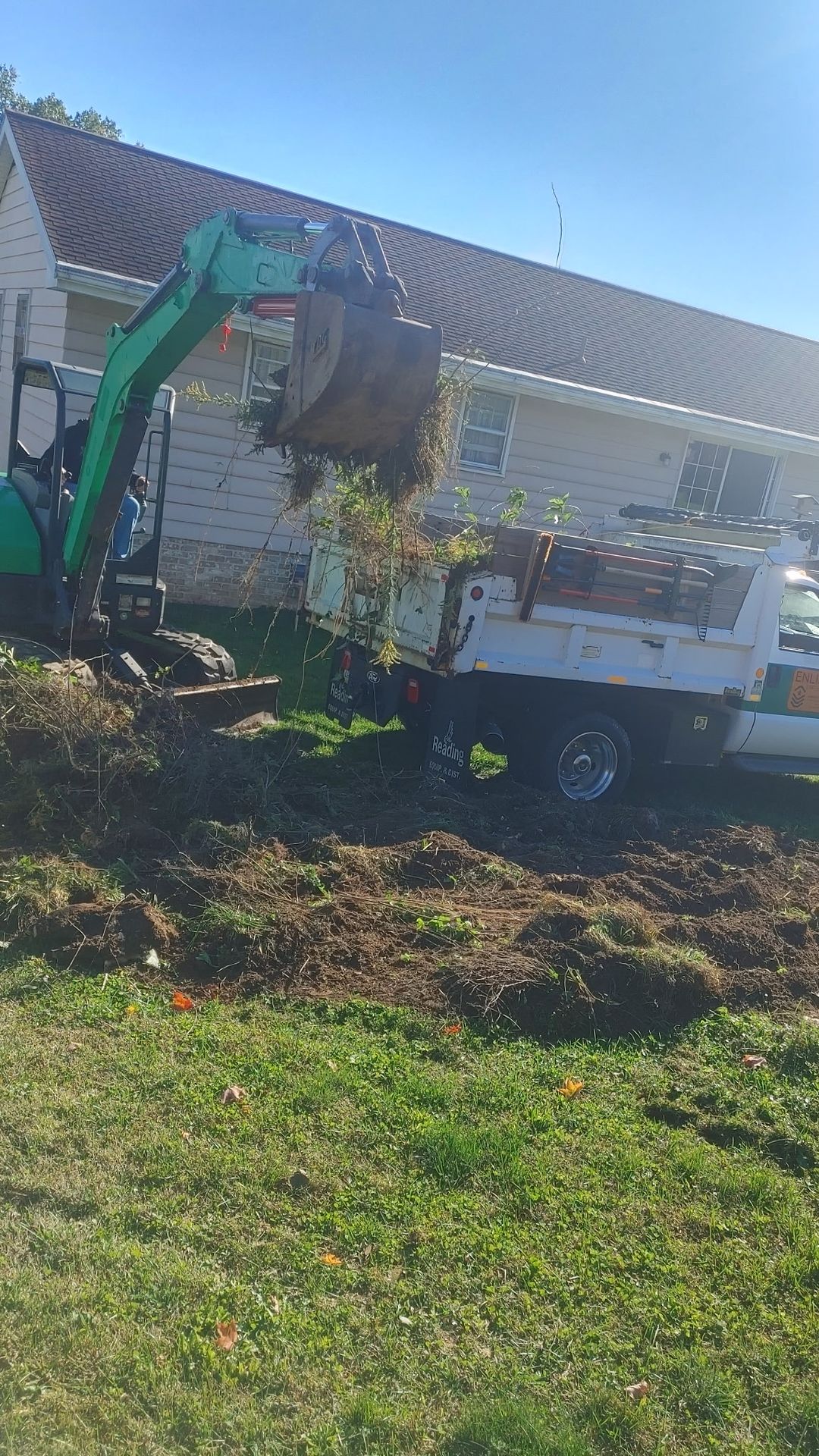 Excavator loading cleared brush and stumps into dump truck