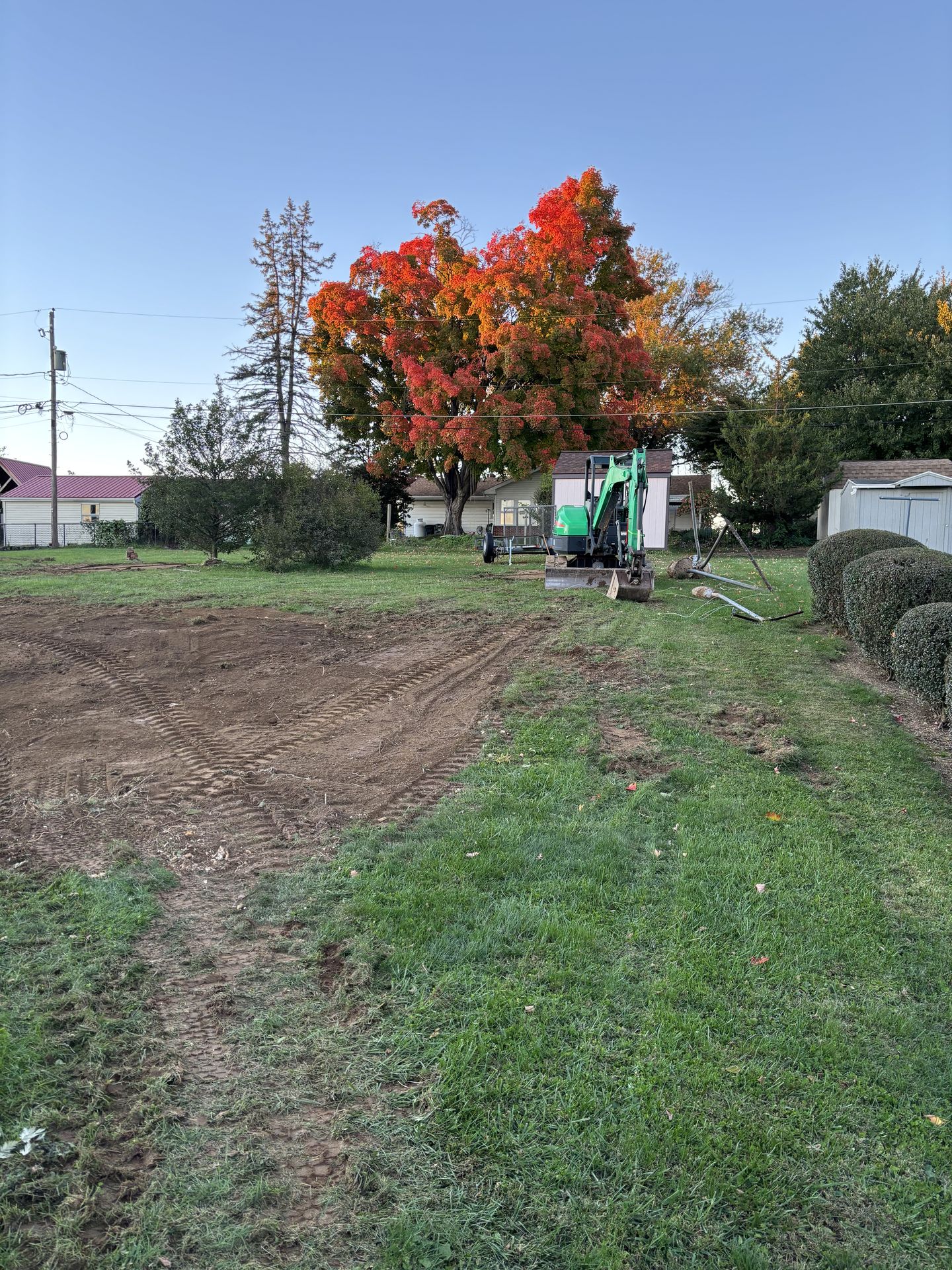 Mini excavator finishing grading work in a cleared backyard